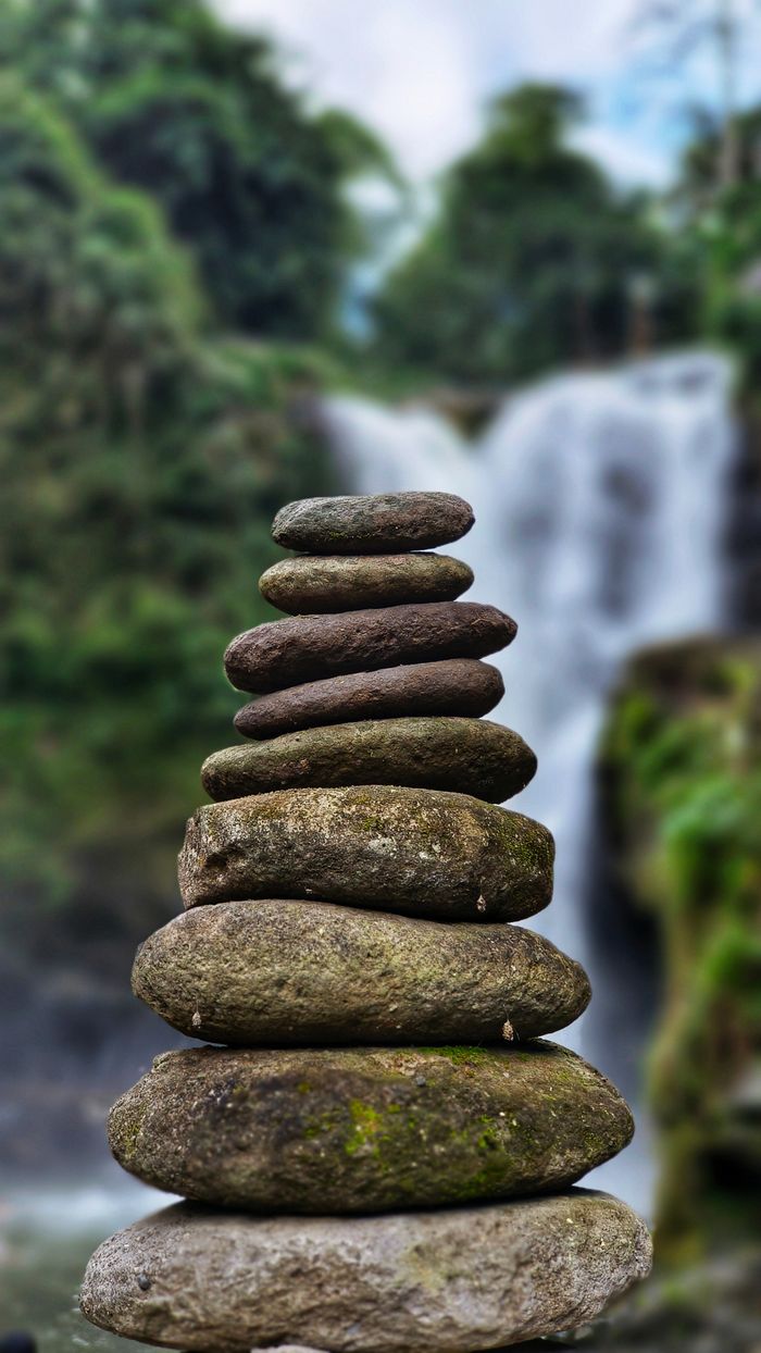 A serene stone cairn stacked in front of a waterfall in Bali, Indonesia.